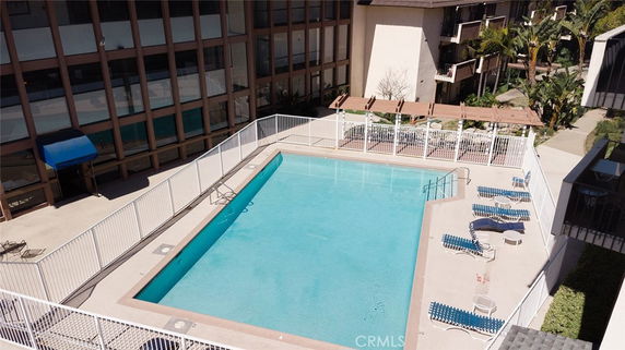 Aerial view of a swimming pool surrounded by a fence in a building complex.