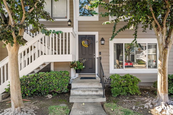 Front view of a house with stairs leading to the entrance and a small porch area.