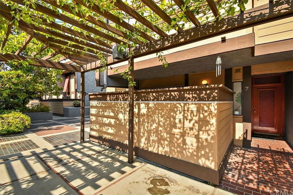 Front view of a house with wooden paneling and a pergola.