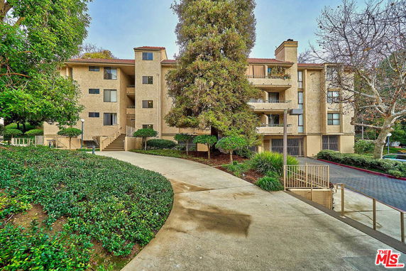 Front view of a multi-story apartment building with a landscaped pathway.