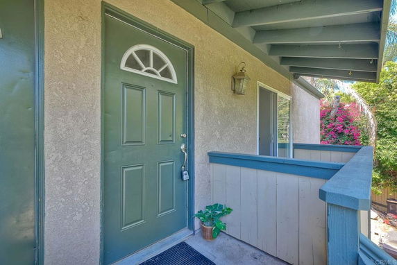 Front view of a house entrance with a green door and small balcony.
