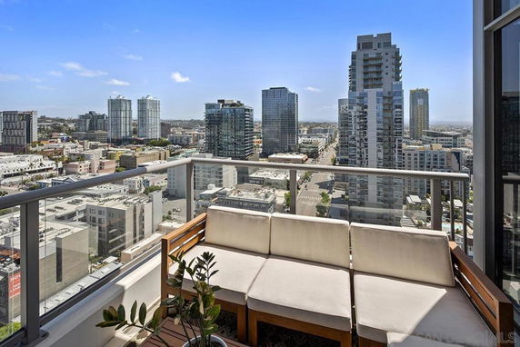 Panoramic view of a cityscape from a balcony with a sofa.