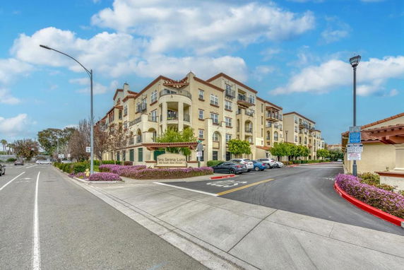 Front view of a multi-story apartment building with balconies and parking area.