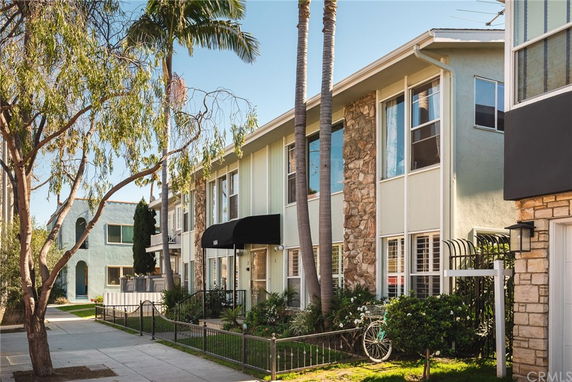 Front view of a multi-story apartment building with a stone facade and large windows.