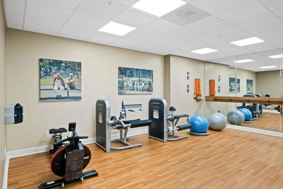 Indoor gym area with exercise equipment and mirrors on the wall.