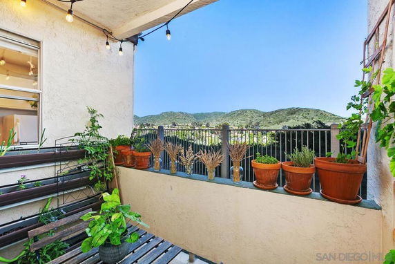 Balcony with potted plants overlooking scenic hills and greenery.