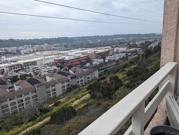 Elevated view of buildings and a shopping center with surrounding greenery.