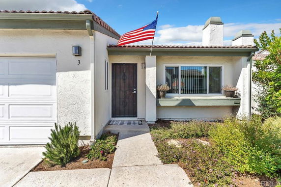 Front view of a single-story house with a garage and an American flag.