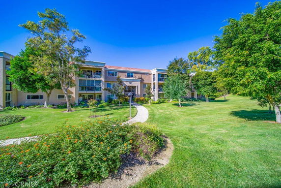 Front view of a multi-story residential building with balconies and a pathway leading up to the entrance.