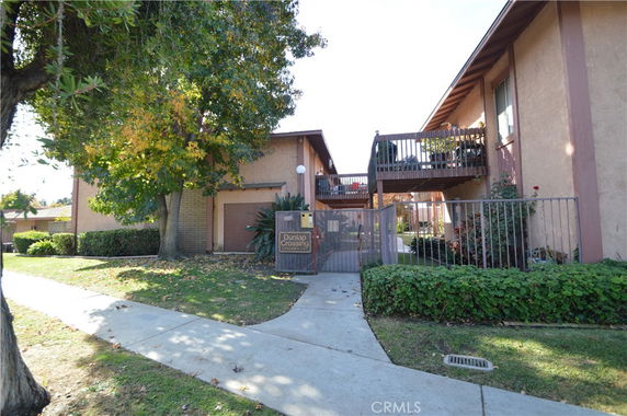 Front view of a multi-story residential building with balconies and an entrance gate.