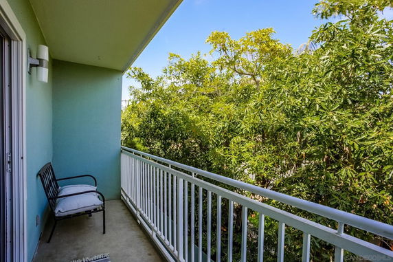 Balcony with railing and seating overlooking trees.