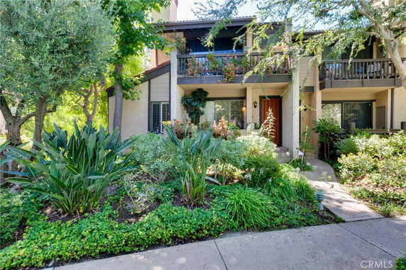 Front view of a two-story house with balconies and a garden.