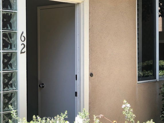 Partial front view of a building entrance with door slightly open.