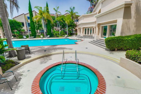 Outdoor swimming pool area with lounge chairs and a hot tub.