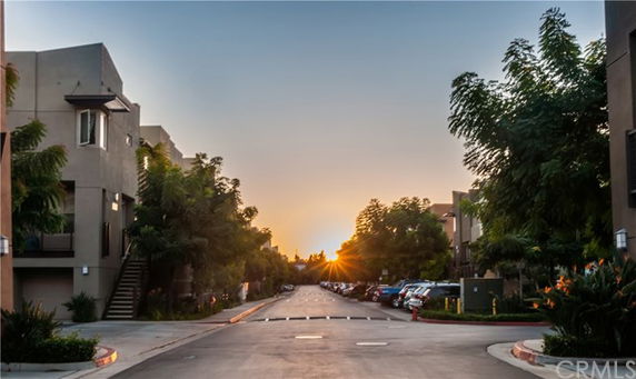 Outdoor parking area with buildings on either side during sunset.