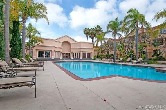 Outdoor swimming pool with surrounding lounge chairs and a building in the background.