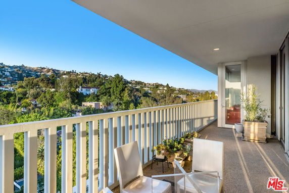 Balcony view overlooking a lush green landscape and distant hills.