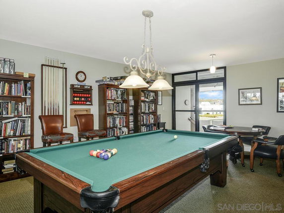 Indoor recreation room with a pool table, bookshelves, and seating area.