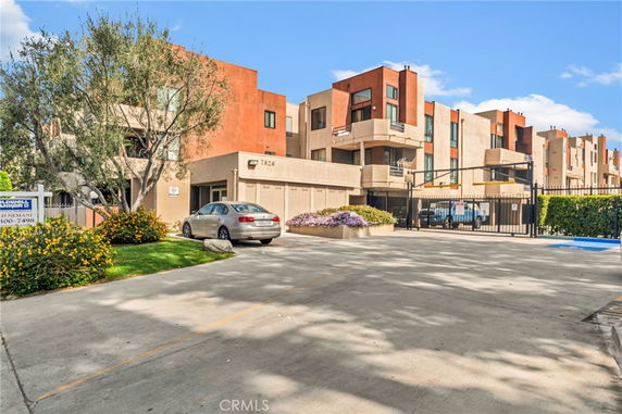 Front view of a multi-story apartment building with a gated parking area.