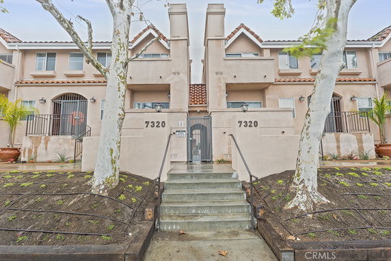 Front view of a two-story residential building with exterior stairs and gated entrance.
