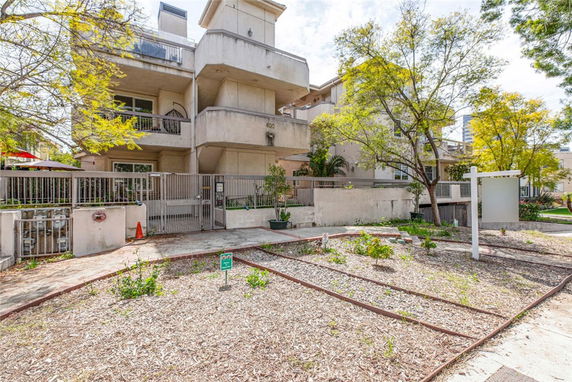 Front view of a multi-story residential building with balconies and a gated entrance.