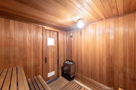 Interior view of a wooden sauna room with benches and a heater.