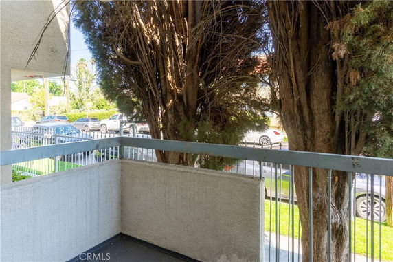 View from a balcony showing trees and parked cars on the street.