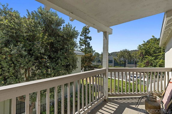 View from a balcony overlooking trees and a distant street.