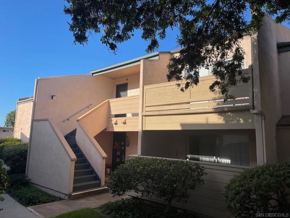 Front view of a two-story apartment building with external staircase and balcony.