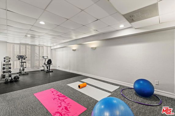 Indoor home gym with exercise equipment and mats.