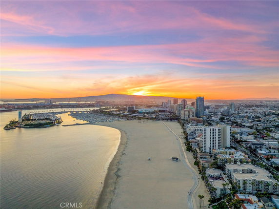 Wide angle view of a coastline with city buildings and a harbor at sunset.