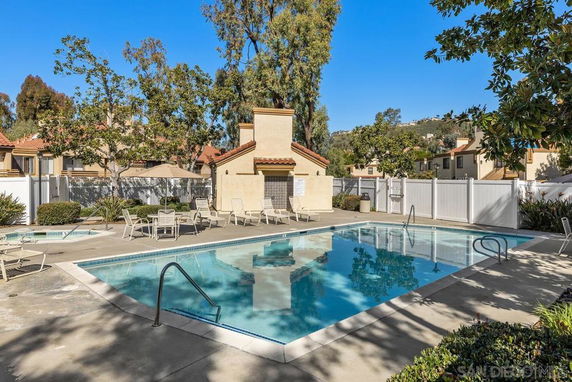 Outdoor swimming pool area with surrounding lounge chairs and small building.