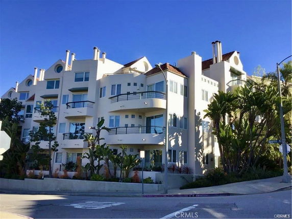 Front view of a multi-story apartment building with balconies and large windows.