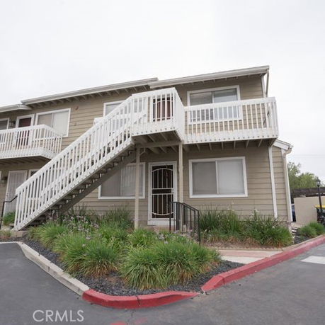 Front view of a two-story building with exterior stairs and balcony.