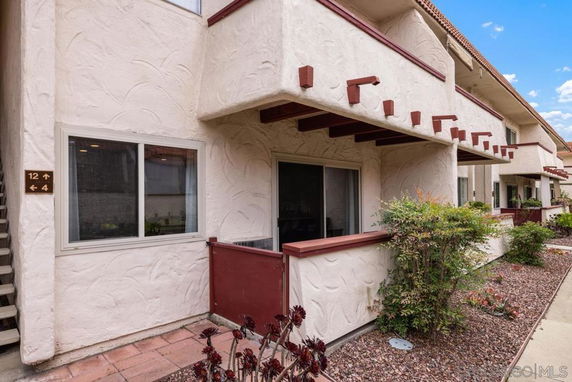 Front view of a multi-story building with beige stucco walls and red trim.