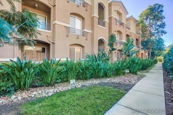 Front view of a multi-story apartment building with balconies and a garden.