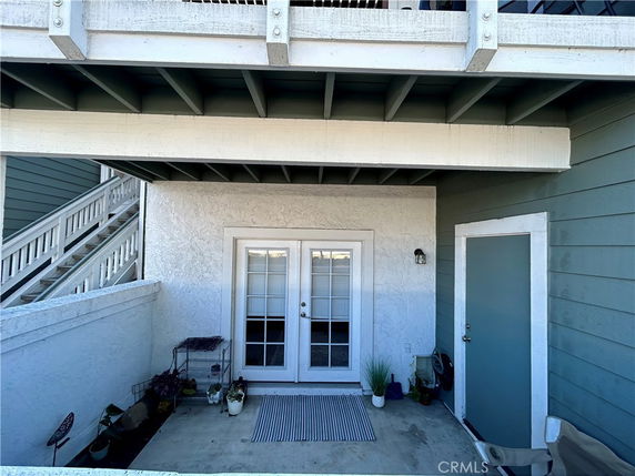 Front view of a building with a small patio and white double doors.