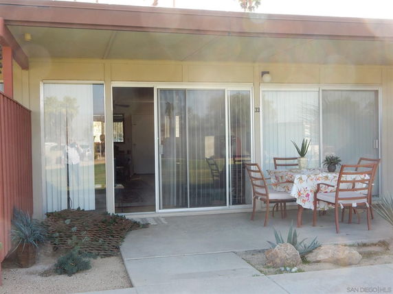 Front view of a single-story house with a small patio area and sliding glass doors.
