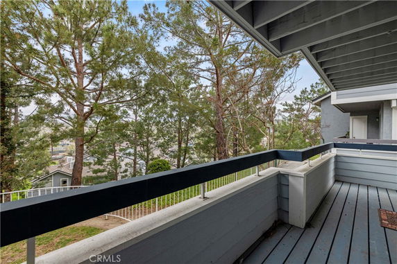 Balcony of a house with view of trees and nearby homes.