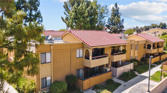Front view of a multi-story apartment building with balconies and red tile roof.