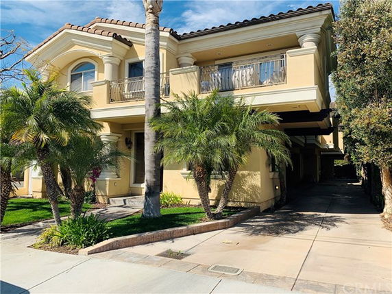 Front view of a two-story house with balconies and an open driveway.