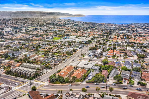 Panoramic view of a coastal residential area with numerous houses and roads, overlooking the ocean.