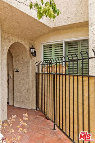 Front view of a house with an arched entryway and iron fence.