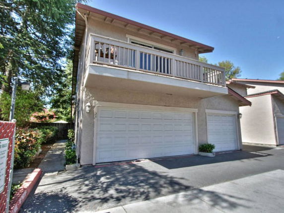 Front view of a two-story house with a balcony and multiple garages.