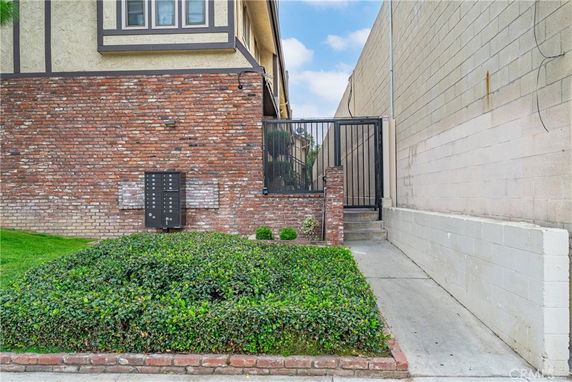 Front view of a brick wall with a gate leading to a building entrance.