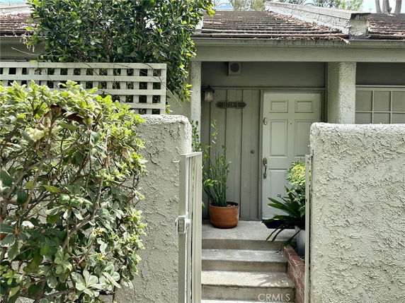 Front view of a house with a small entrance gate and greenery.