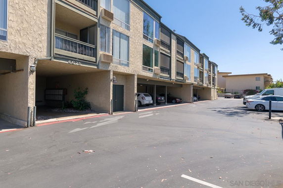 Outdoor parking area of a multi-story building with covered parking spaces.