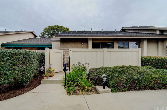 Front view of a single-story house with a small entrance gate and shrubbery.
