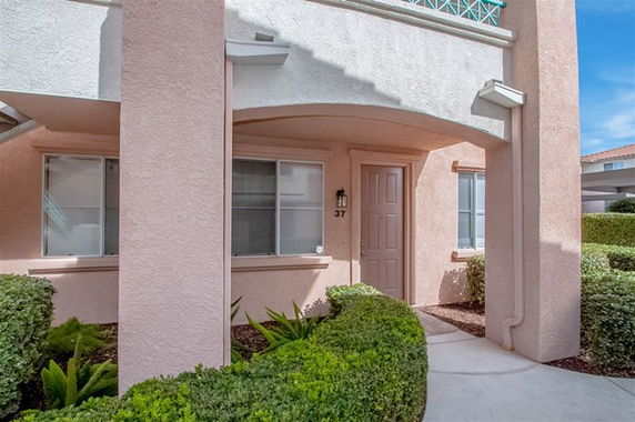Front view of a house with a covered entrance and light pink stucco exterior.