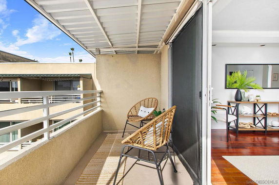 View from a balcony with two chairs overlooking neighboring buildings.